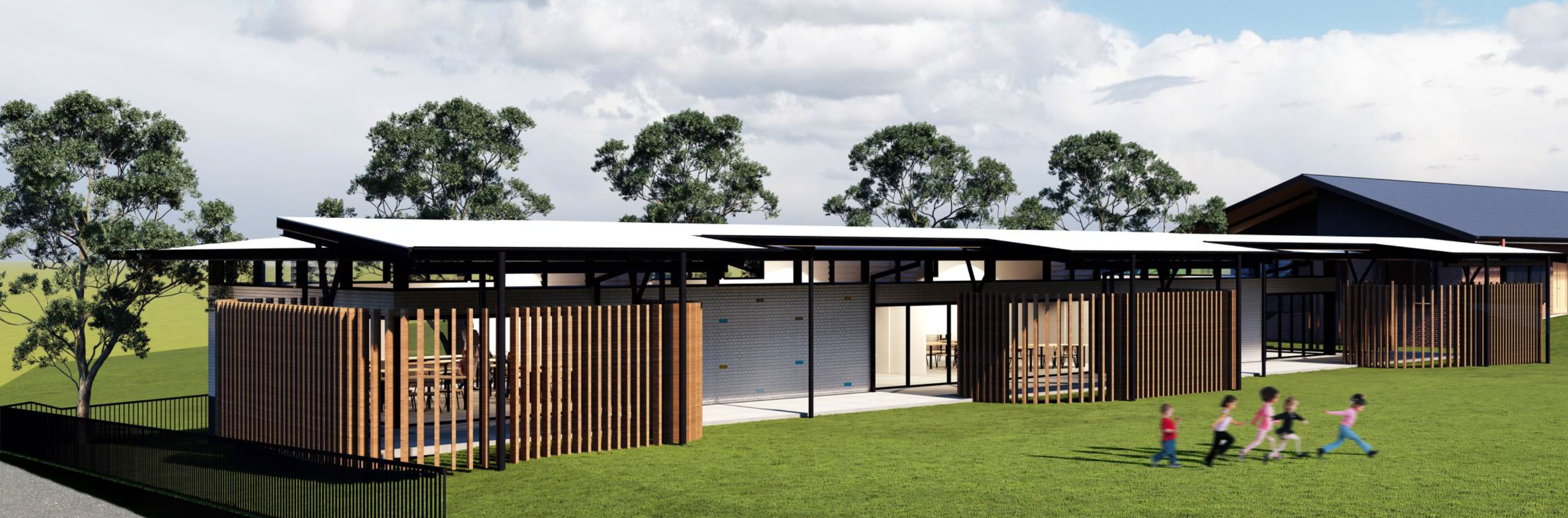 Modern single-storey school building with covered outdoor areas and timber screens, with students running on the grass in front